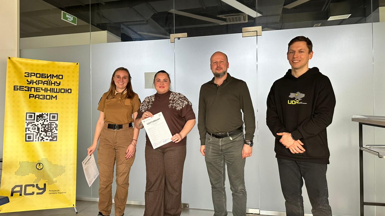 інструктори АСУ вручають сертифікат учасниці проєкту "Вона демінерка"